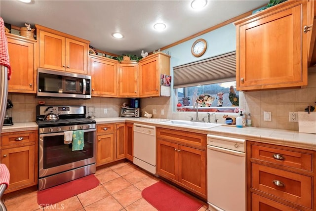 kitchen with light tile patterned floors, sink, appliances with stainless steel finishes, and tasteful backsplash