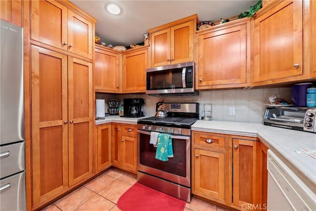 kitchen featuring light tile patterned floors, appliances with stainless steel finishes, and decorative backsplash