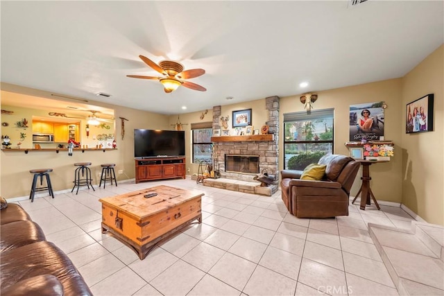 tiled living room featuring ceiling fan and a fireplace