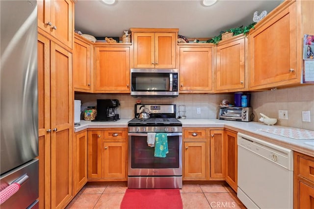 kitchen with tasteful backsplash, light tile patterned floors, and appliances with stainless steel finishes