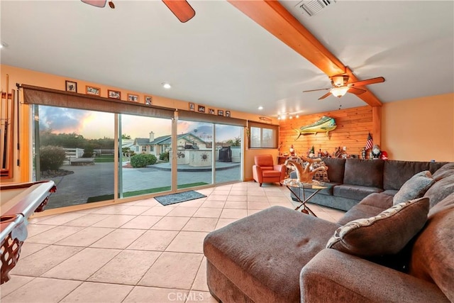 tiled living room featuring beam ceiling, ceiling fan, and wooden walls