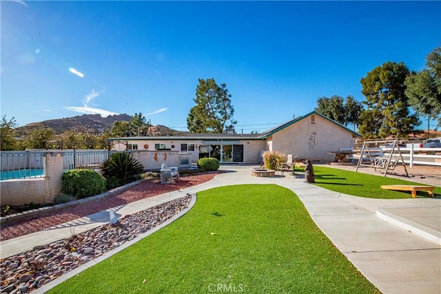 back of property with a mountain view and a lawn