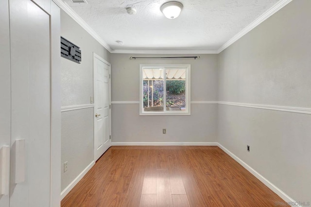 spare room with a textured ceiling, ornamental molding, and light hardwood / wood-style floors