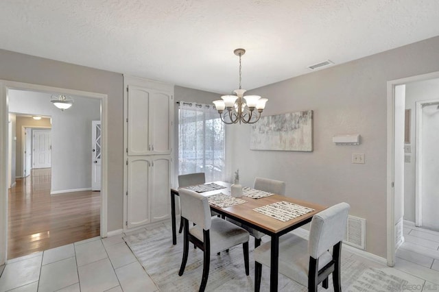 tiled dining room featuring an inviting chandelier and a textured ceiling