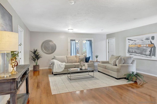 living room with light hardwood / wood-style floors, a textured ceiling, and french doors