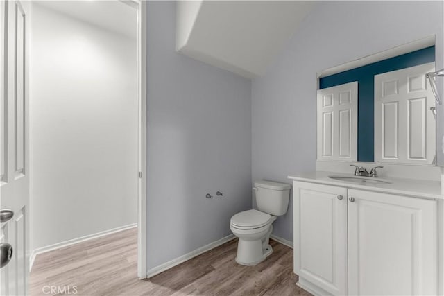 bathroom with hardwood / wood-style flooring, lofted ceiling, vanity, and toilet