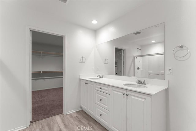 bathroom featuring hardwood / wood-style flooring, vanity, and an enclosed shower