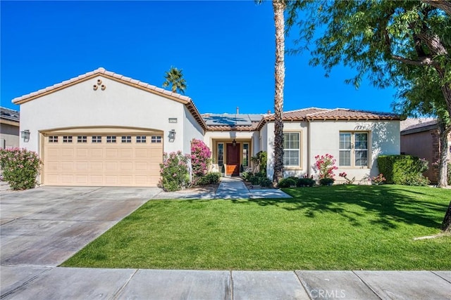 mediterranean / spanish-style house featuring a front yard, a garage, and solar panels