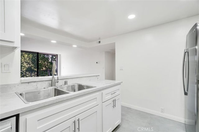 kitchen featuring white cabinets, sink, and stainless steel refrigerator