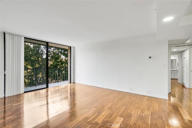 unfurnished room featuring expansive windows, a wealth of natural light, and light hardwood / wood-style flooring