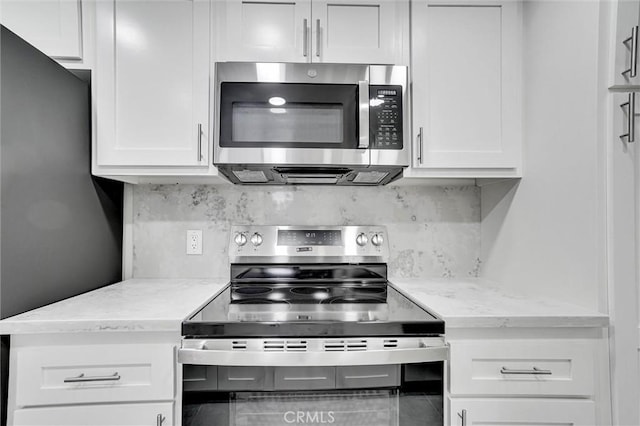 kitchen featuring tasteful backsplash, appliances with stainless steel finishes, white cabinetry, and light stone counters