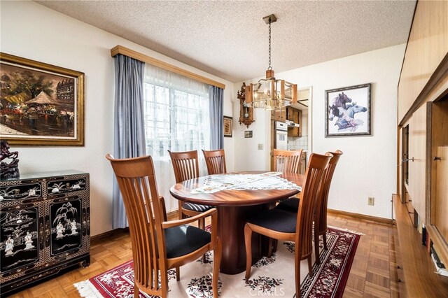 dining space with parquet flooring, a textured ceiling, and a notable chandelier