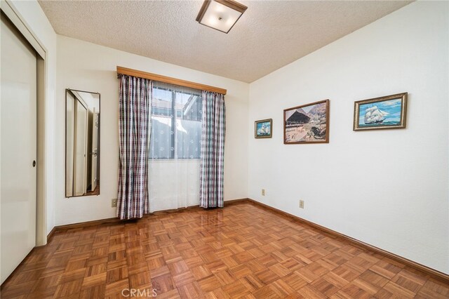 empty room featuring parquet flooring and a textured ceiling