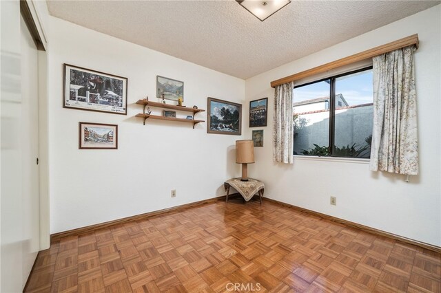 empty room with a textured ceiling, light parquet floors, and a mountain view