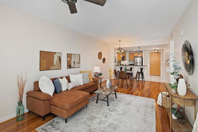 living room featuring ceiling fan with notable chandelier and hardwood / wood-style floors