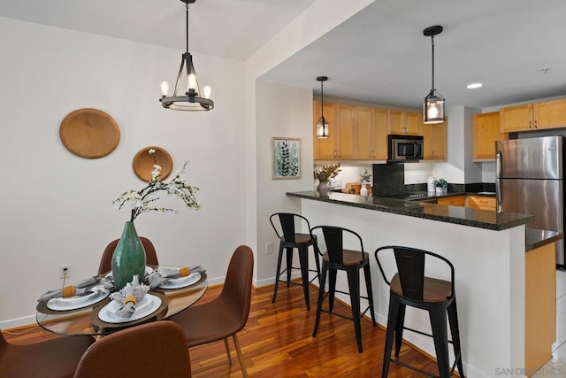 kitchen with hanging light fixtures, kitchen peninsula, and tasteful backsplash