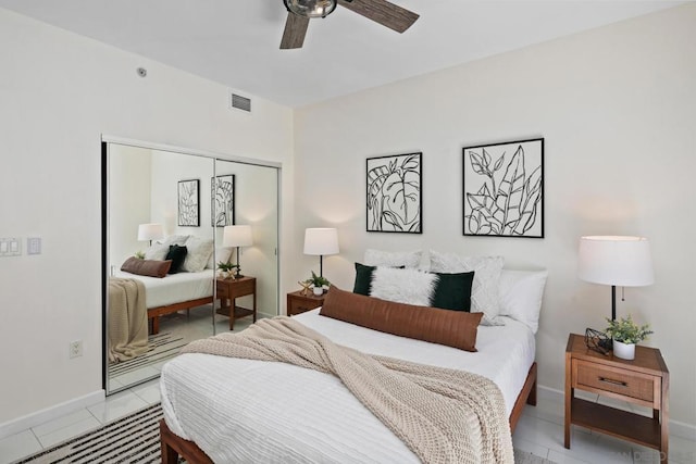 bedroom with ceiling fan, light tile patterned floors, and a closet