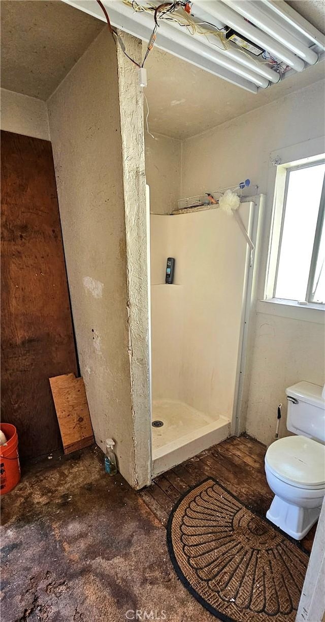 bathroom featuring walk in shower and toilet