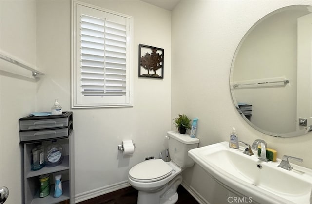 bathroom with toilet, baseboards, and a sink