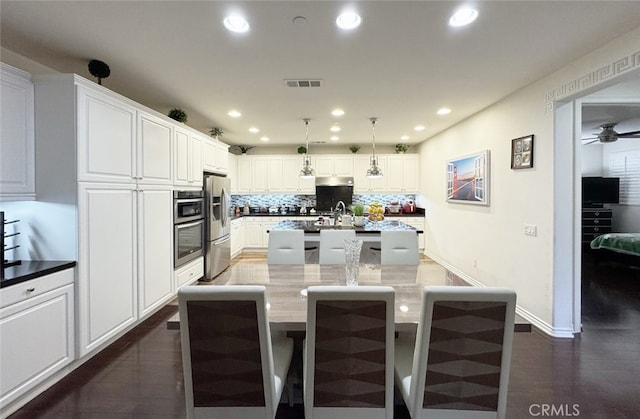 kitchen featuring a center island with sink, backsplash, white cabinetry, and stainless steel fridge with ice dispenser