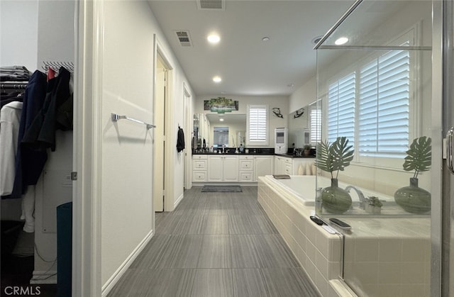 full bath featuring vanity, a garden tub, a shower, and visible vents