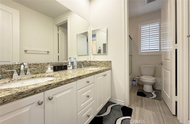 bathroom featuring double vanity, toilet, a shower, and a sink