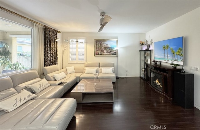 living room with a healthy amount of sunlight, baseboards, a lit fireplace, and wood finished floors