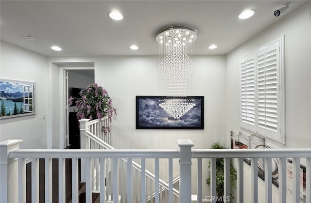 hallway with recessed lighting, an upstairs landing, and a chandelier