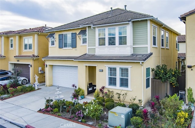 view of front of house featuring stucco siding, concrete driveway, a tile roof, and an attached garage