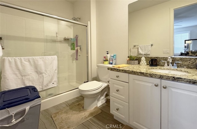 bathroom featuring toilet, a stall shower, and vanity