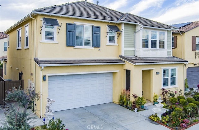 view of property with stucco siding, concrete driveway, a tile roof, and a garage