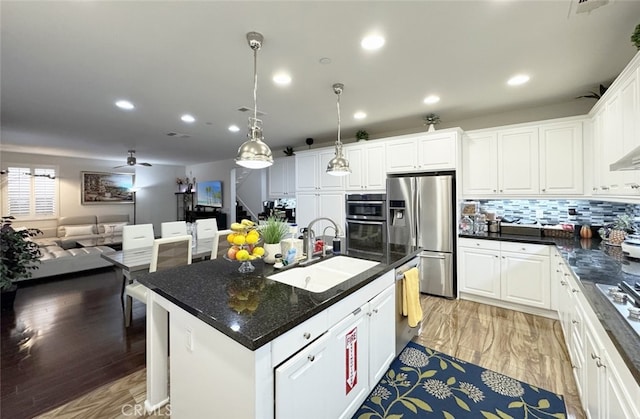 kitchen featuring recessed lighting, a sink, white cabinets, appliances with stainless steel finishes, and open floor plan