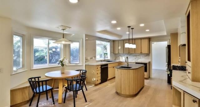 kitchen featuring decorative light fixtures, sink, light hardwood / wood-style floors, and a raised ceiling