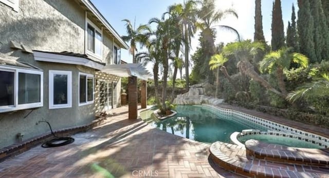 view of swimming pool featuring a patio and an in ground hot tub