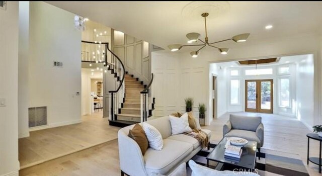 living room with light wood-type flooring, an inviting chandelier, and french doors