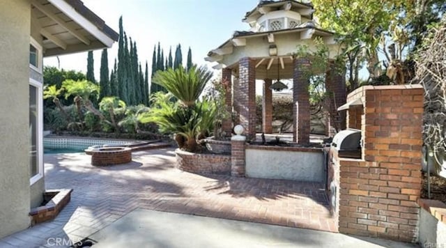 view of patio / terrace with a swimming pool, an outdoor fire pit, and exterior kitchen