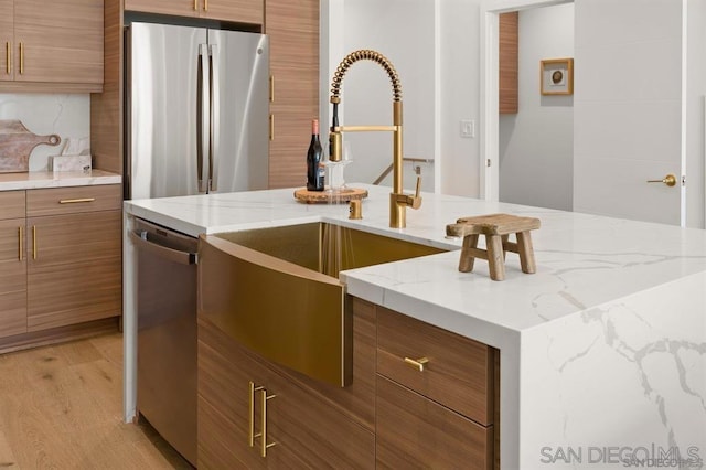 kitchen with stainless steel appliances, sink, light hardwood / wood-style floors, and decorative backsplash