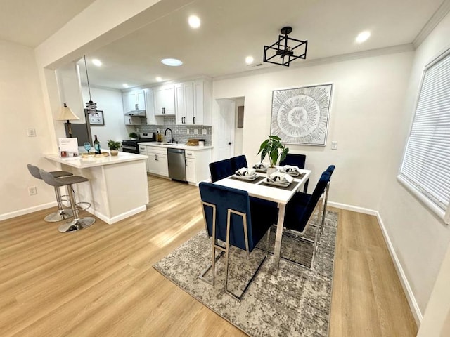 dining room with ornamental molding, sink, and light wood-type flooring