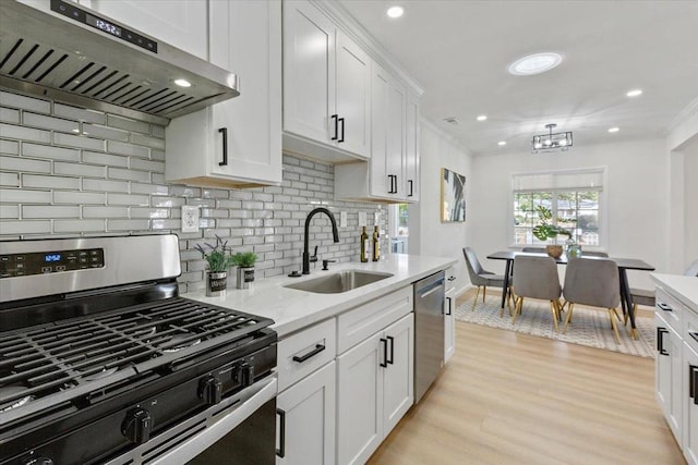 kitchen with sink, white cabinetry, light wood-type flooring, appliances with stainless steel finishes, and range hood