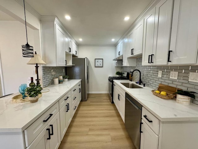 kitchen featuring sink, appliances with stainless steel finishes, light stone countertops, white cabinets, and decorative light fixtures