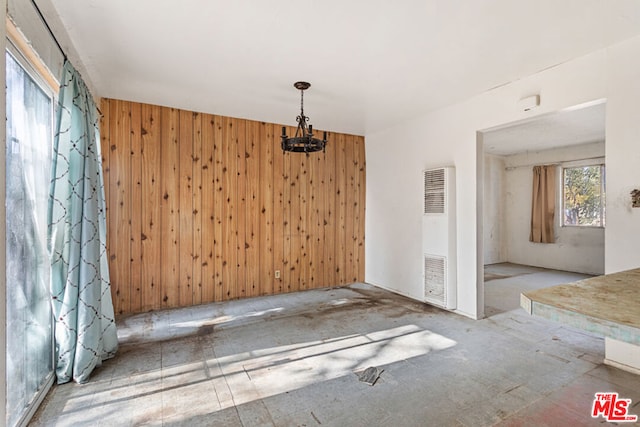 unfurnished dining area featuring a notable chandelier and wood walls