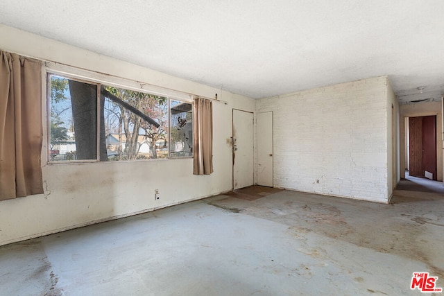 empty room with concrete floors and brick wall