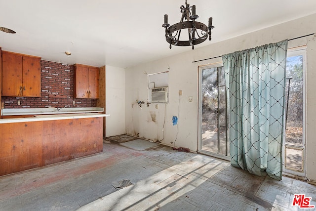 kitchen featuring kitchen peninsula, a notable chandelier, a wealth of natural light, and a wall unit AC