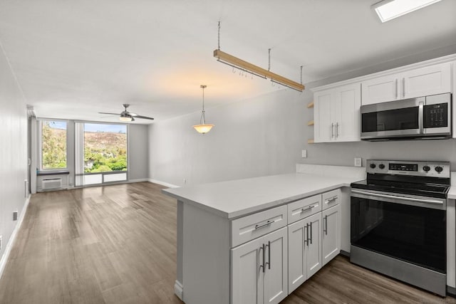 kitchen with white cabinetry, kitchen peninsula, stainless steel appliances, dark wood-type flooring, and hanging light fixtures