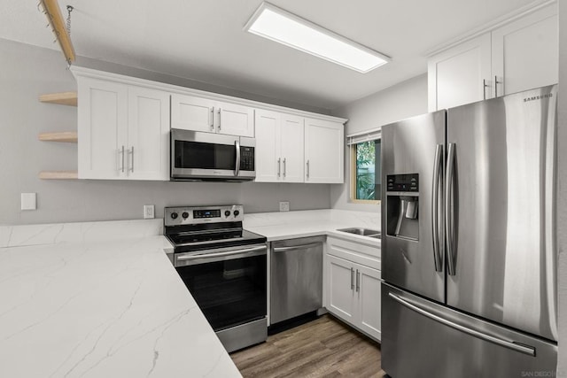 kitchen with dark hardwood / wood-style floors, stainless steel appliances, white cabinetry, and light stone counters