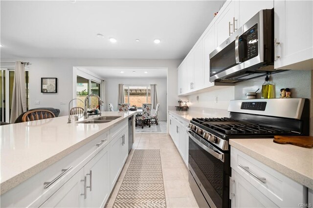 kitchen with sink, white cabinetry, light tile patterned floors, and stainless steel appliances