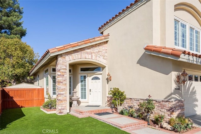 doorway to property with a garage and a yard