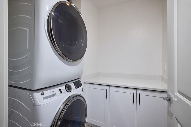 clothes washing area featuring cabinets and stacked washer and dryer