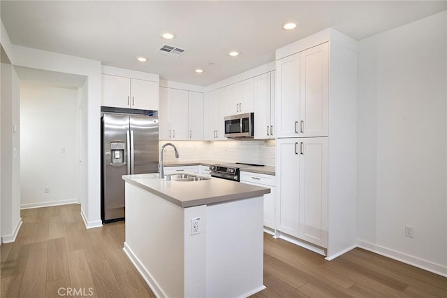 kitchen featuring sink, white cabinetry, light wood-type flooring, stainless steel appliances, and a kitchen island with sink