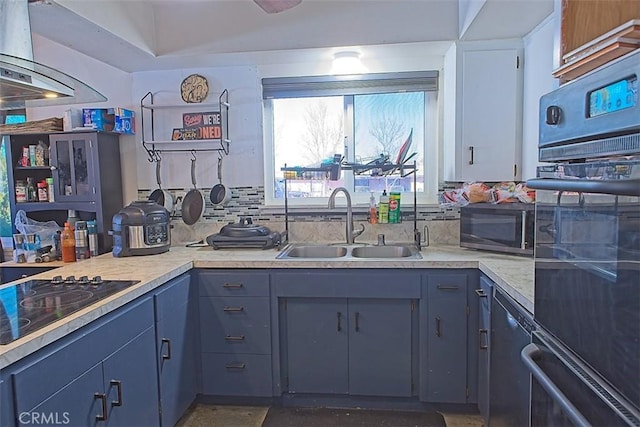 kitchen featuring blue cabinetry, sink, range hood, decorative backsplash, and black appliances